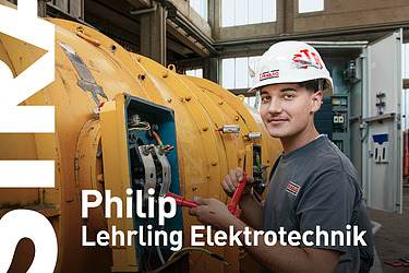 Lehrling sitzt auf der Kette einer Baumaschine