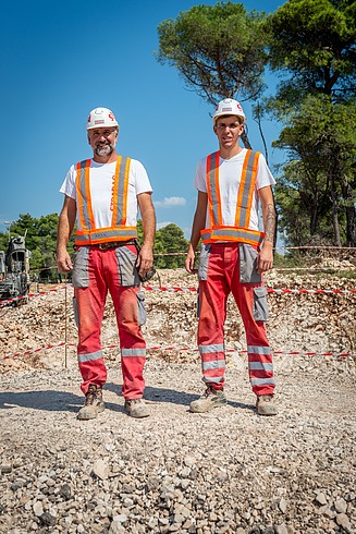 Mlađi i stariji kolega na gradilištu gledaju u kameru