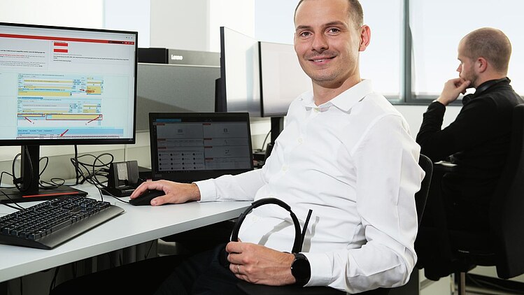 Karijerna priča Matija Habuzin 01 Kolega u uredu sjedi za stolom, ima slušalice u ruci