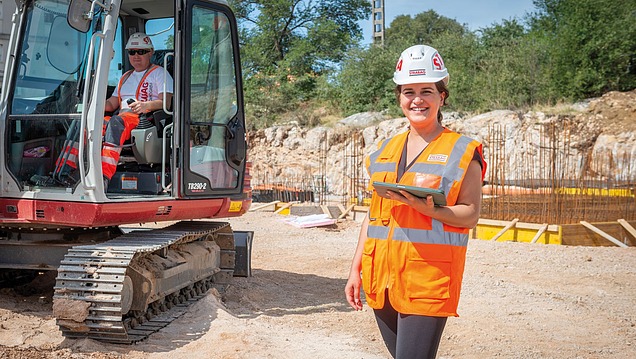 Kolegica na gradilištu s kacigom gleda u kameru i smije se