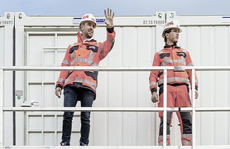 Photo Two men standing by the container left man raised hand