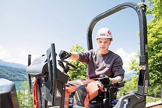 Photo An apprentice sits in the driver's seat and looks into the camera