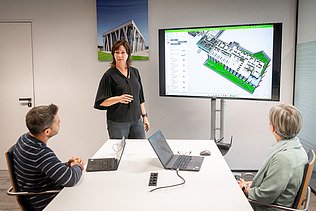 Ein Polier erklärt seinem Team etwas auf einem Tablet