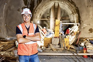 Florian Fuchs, chef de chantier, se tient sur un chantier de construction avec un tampon et un casque