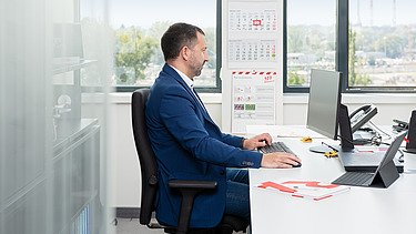 Kolega sedi za stolom u kancelariji i gleda u ekran