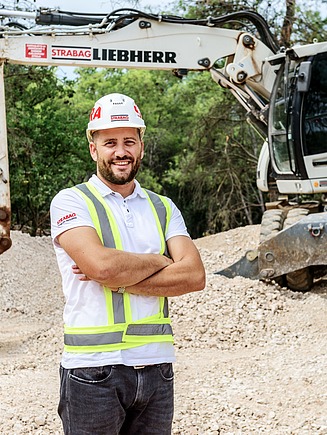 Kolega na gradilištu, iza njega je bager