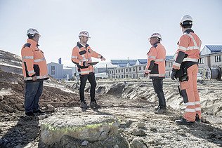 Photo Four men with helmet and jacket facing each other on construction site