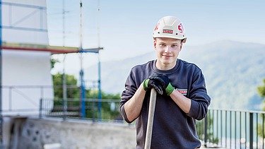 Photo: An apprentice leans on a shovel and looks into the camera