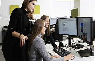 Marija sits with two colleagues in front of a pc
