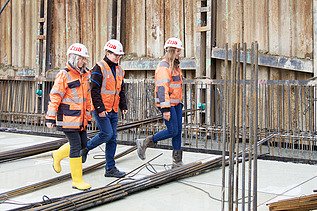Foto von drei ZÜBLIN-Kolleg:innen, die über die Baustelle laufen