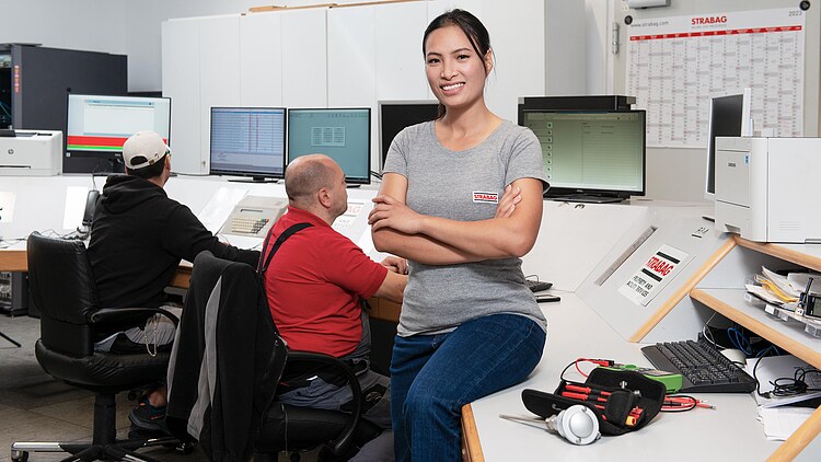 Foto von Frau, die auf einem Tisch sitzt und in die Kamera lächelt