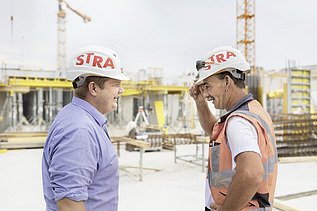 Photo Two men with helmet facing are talking at the construction site