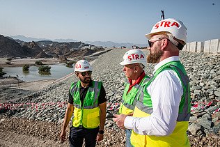 Colleagues stand together on a dam construction site in Oman