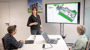 Ein Polier erklärt seinem Team etwas auf einem Tablet