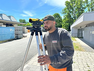 Kazim, road construction apprentice with measuring device