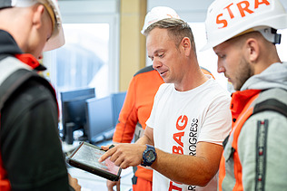 A foreman explains something to his team on a tablet