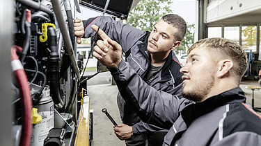 Foto Zwei Männer arbeiten bei einem Gerät der vordere zeigt hinauf