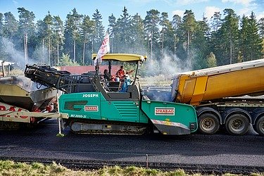STRABAG Fertiger während der Arbeit im Hintergrund ein Wald