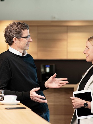 Picture of two colleagues talking in the office kitchenette