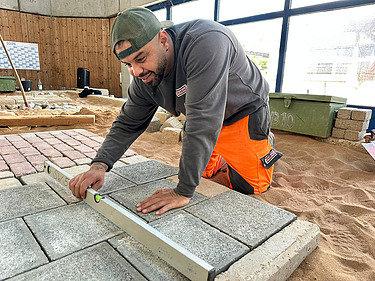 Kazim, Auszubildender im Straßenbau beim Pflastern