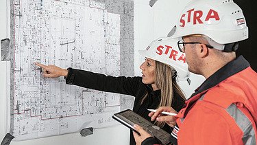 Photo Woman pointing at plan Man looking at plan