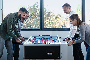 Fotografie Čtyři lidé na fotbalovém stole stolní fotbal