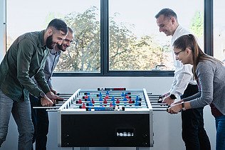 Fotografija četvoro kolega koji igraju stoni fudbal