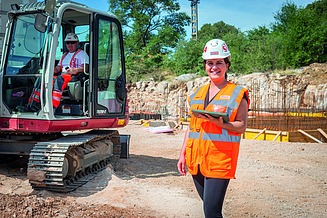 Kolegica sjedi u uredu za stolom i gleda u kameru