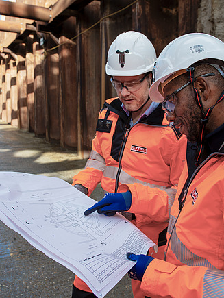 Three men around a plan on a construction site