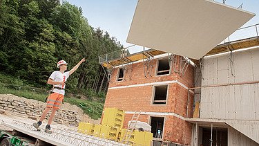 Photo: A construction worker directs a concrete slab hanging from a crane.