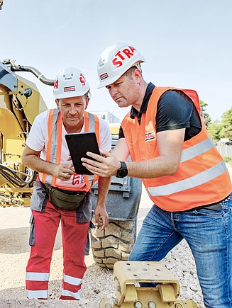 Fotografija kolega na gradilištu koji gledaju u tablet