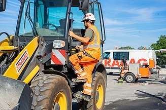 Mitarbeiter STRABAG im Bagger mit Geräten im Hintergrund