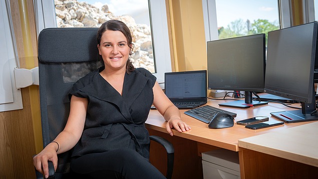 Kolegica sjedi za stolom i gleda u kameru