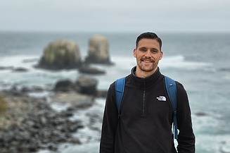 Junger Mann an einer Klippe, Meer im Hintergrund