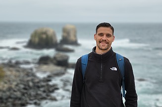 Young man on a cliff, sea in the background