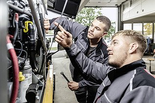 Foto Zwei Männer arbeiten bei einem Gerät der vordere zeigt hinauf