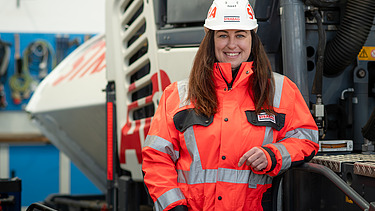 Fotografia kolegyne, ktorá sa opiera o stavebný stroj