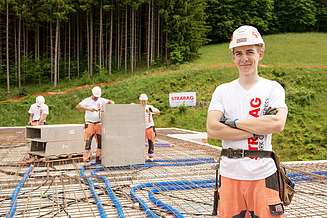 A STRABAG appentice standing in the front while other apprentices work in the background