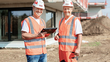 Photo technician standing next to employee with construction helmet pointing