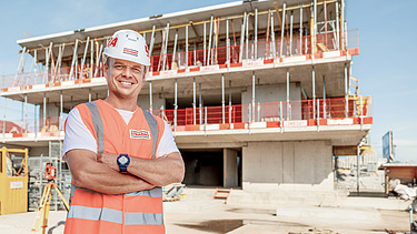 Photo Man with helmet stands infront of construction 