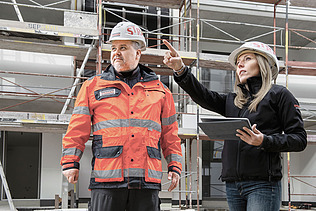 Photo Two people on construction site woman pointing up left